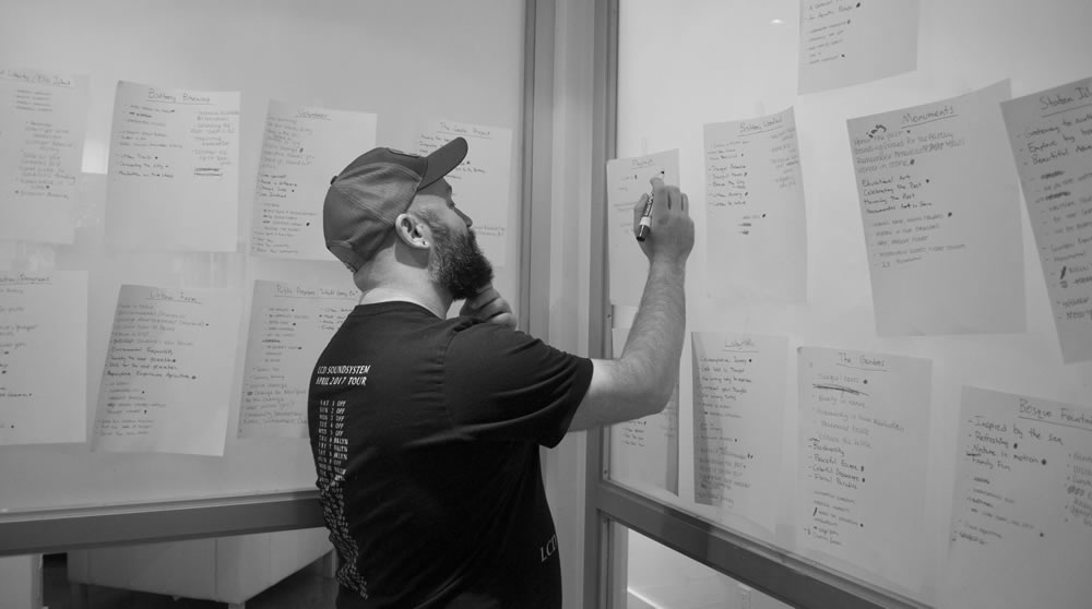 A man writing on a piece of paper taped to the wall